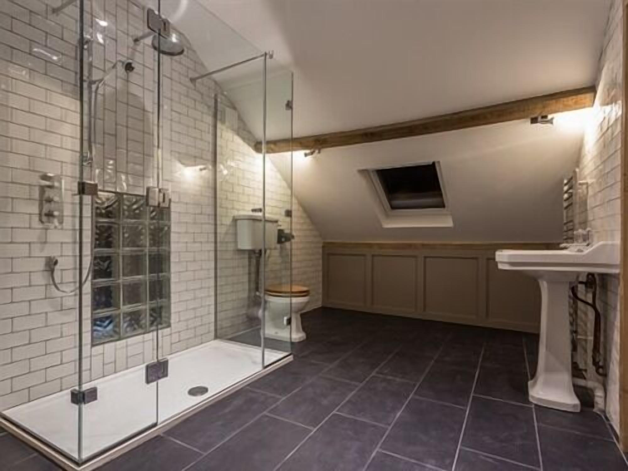 A bathroom with a glass shower enclosure, a white toilet, and a pedestal sink.