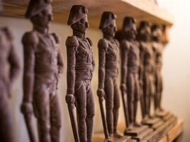Una hilera de estatuas de madera sobre un estante.