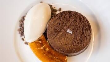 Ein Dessertteller mit Schokoladenkuchen, einer Kugel Eis und einem Stück Obst.