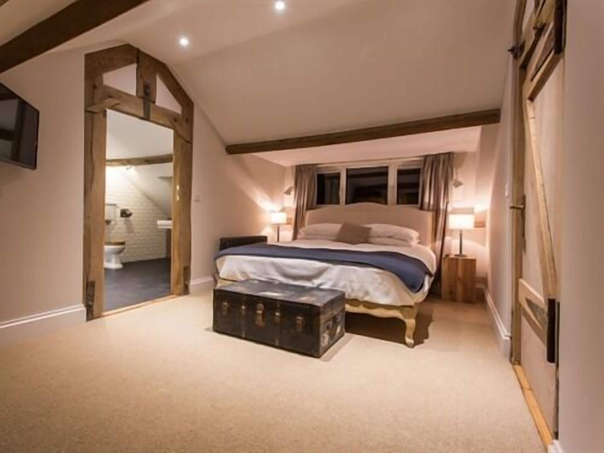 A bedroom with a large bed, a wooden chest, and a small bedside table.