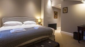 A bedroom with a large bed, a bedside table, a radiator, and a suitcase. - The Redan (Radstock)