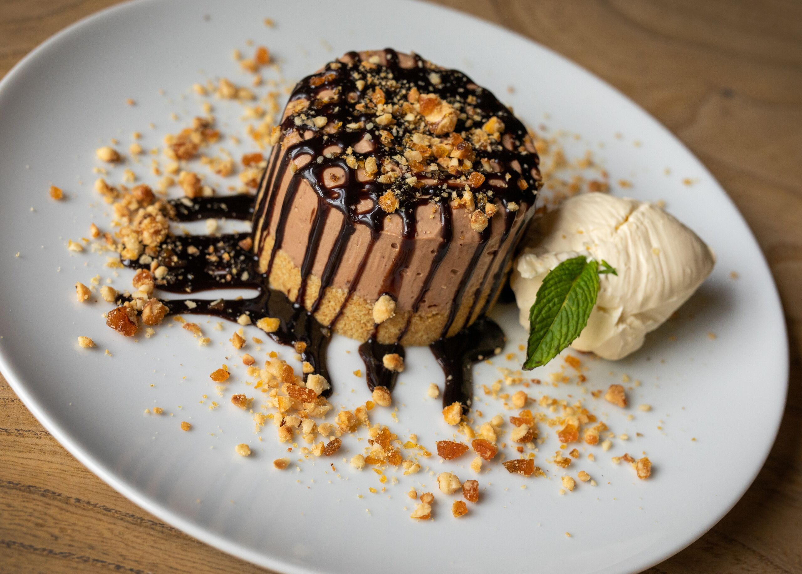A dessert on a plate with crumbled topping and a mint leaf.