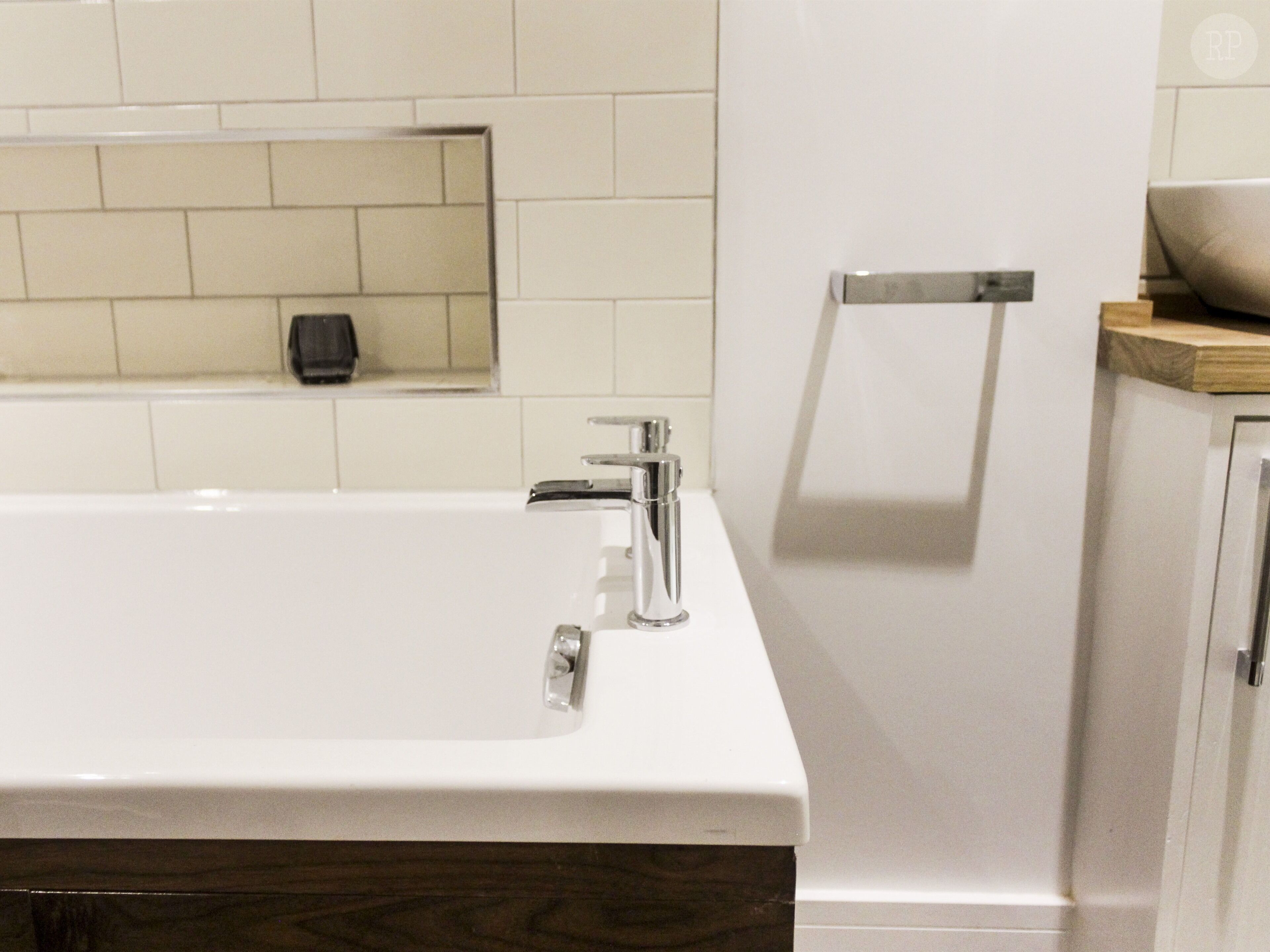 A modern bathroom with a white sink, chrome faucet, and a wooden countertop.