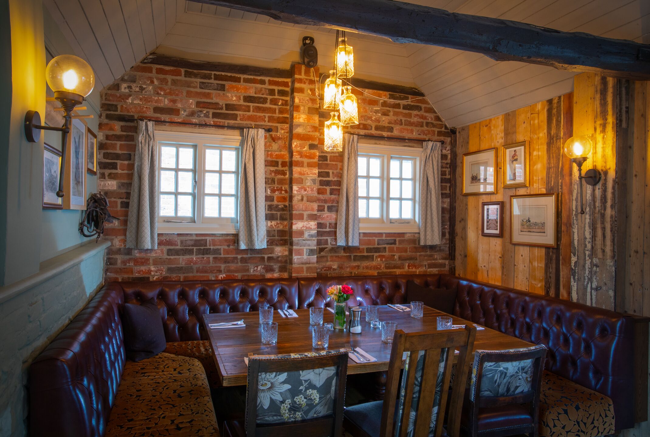 Ein gemütliches Restaurant mit Backsteinwand, Holzbalkendecke und einer langen Sitzbank.