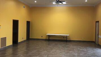 A spacious room with yellow walls, a ceiling fan, recessed lighting, and a bench.
