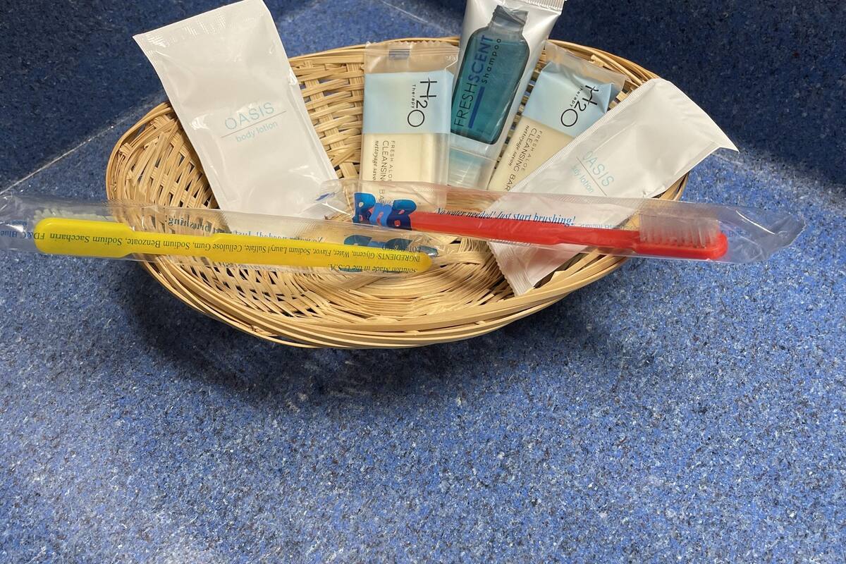 Ein Korbkörbchen auf einer blauen Arbeitsplatte mit Pflegeprodukten wie Körperlotion, Shampoo und einer Zahnbürste.