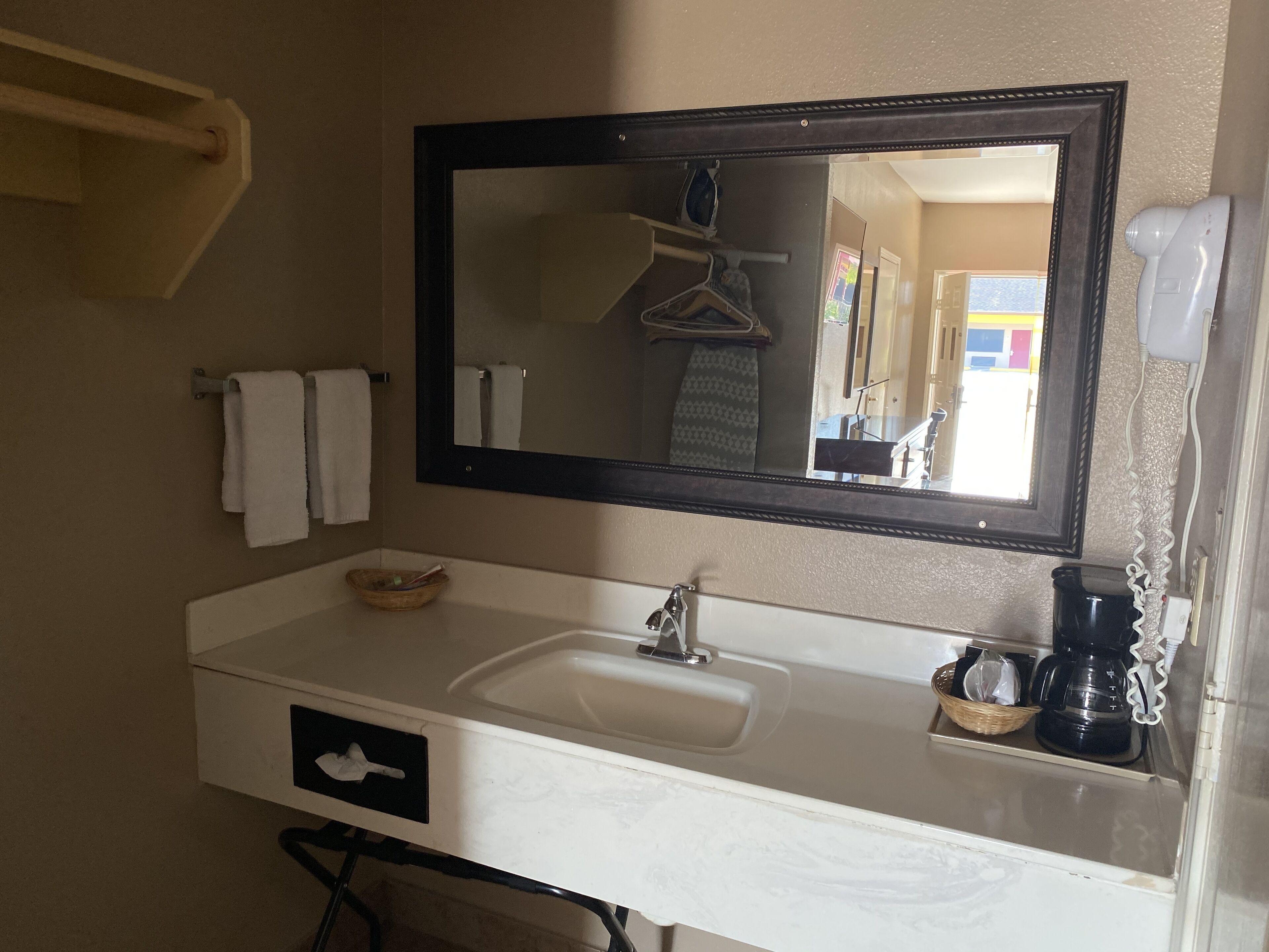 A bathroom with a white sink, a mirror, a towel rack, and a hairdryer.