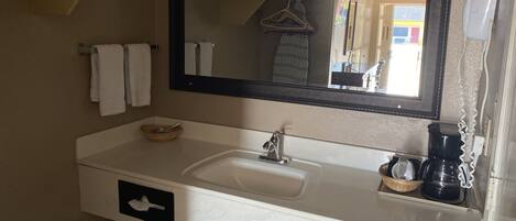 A bathroom with a white sink, a mirror, a towel rack, and a hairdryer.