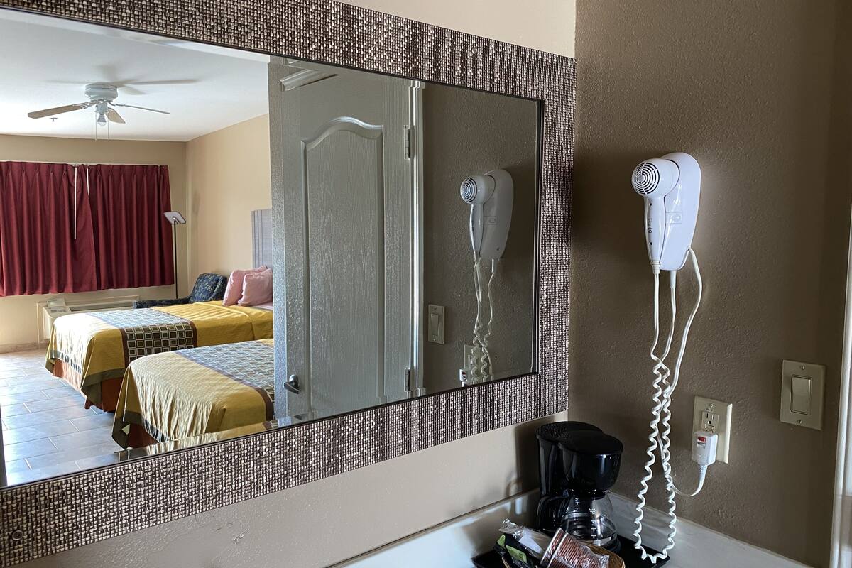 Ein Hotelzimmer mit Bett, Spiegel, Haartrockner, Kaffeemaschine und einem Korb.