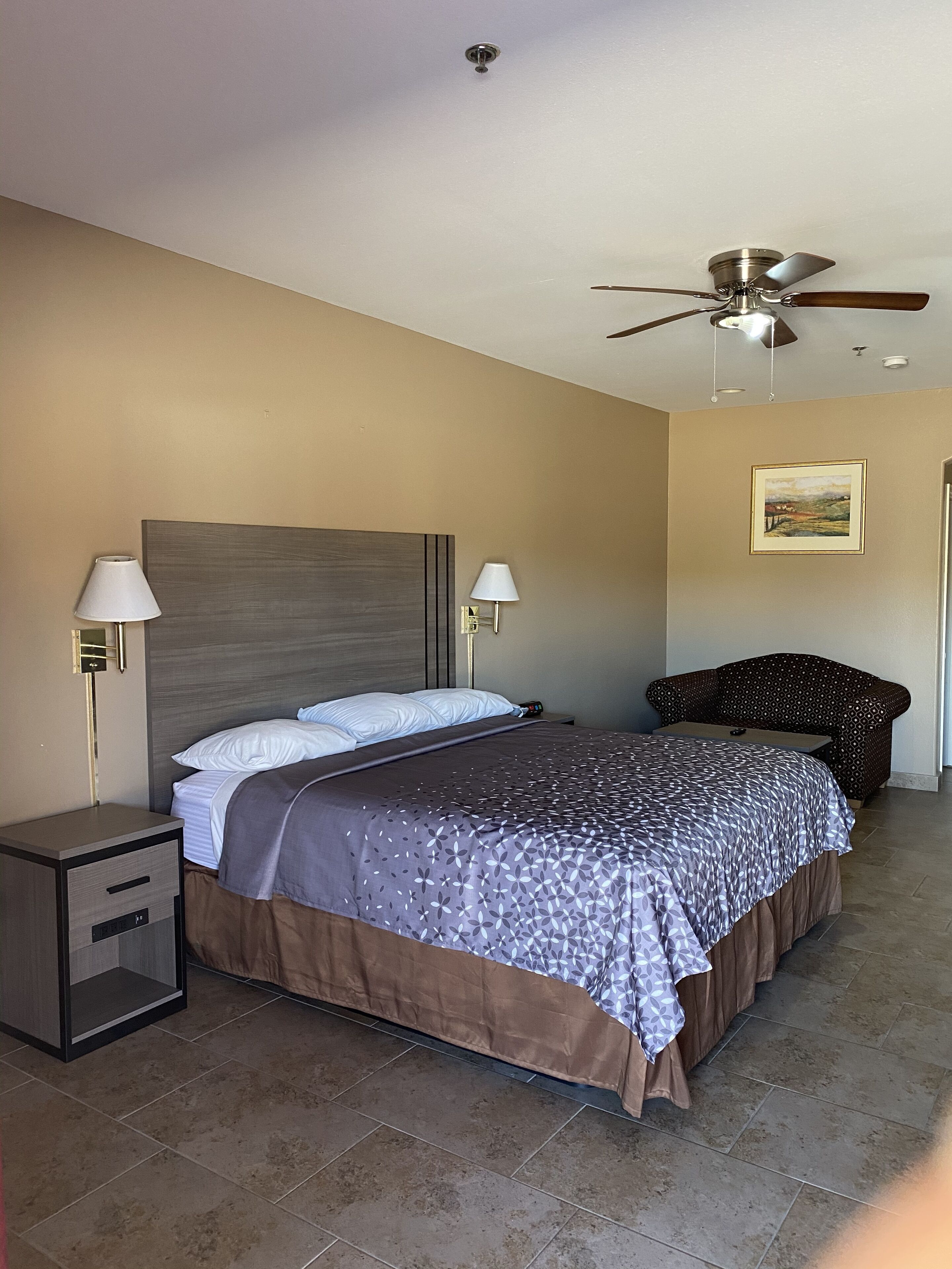 A bedroom with a bed, nightstands, a ceiling fan, and a chair.