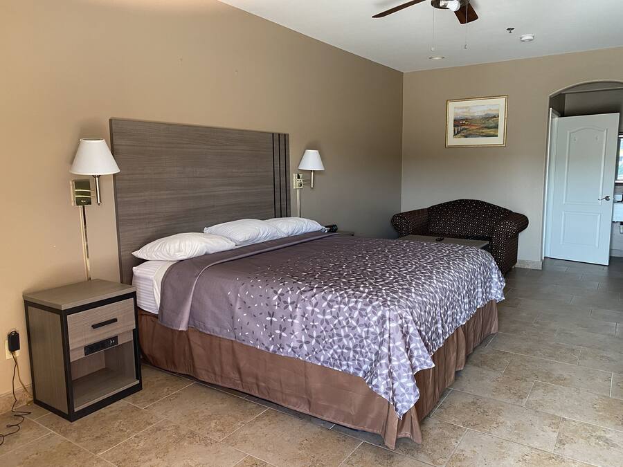 A bedroom with a bed, bedside lamps, a nightstand, a chair, and a door.