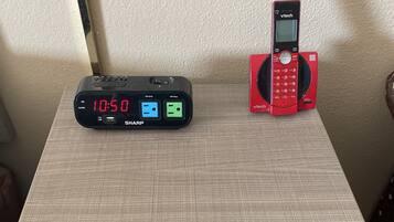 A desk with a digital clock displaying 10:50, a red phone, and a USB charging station.