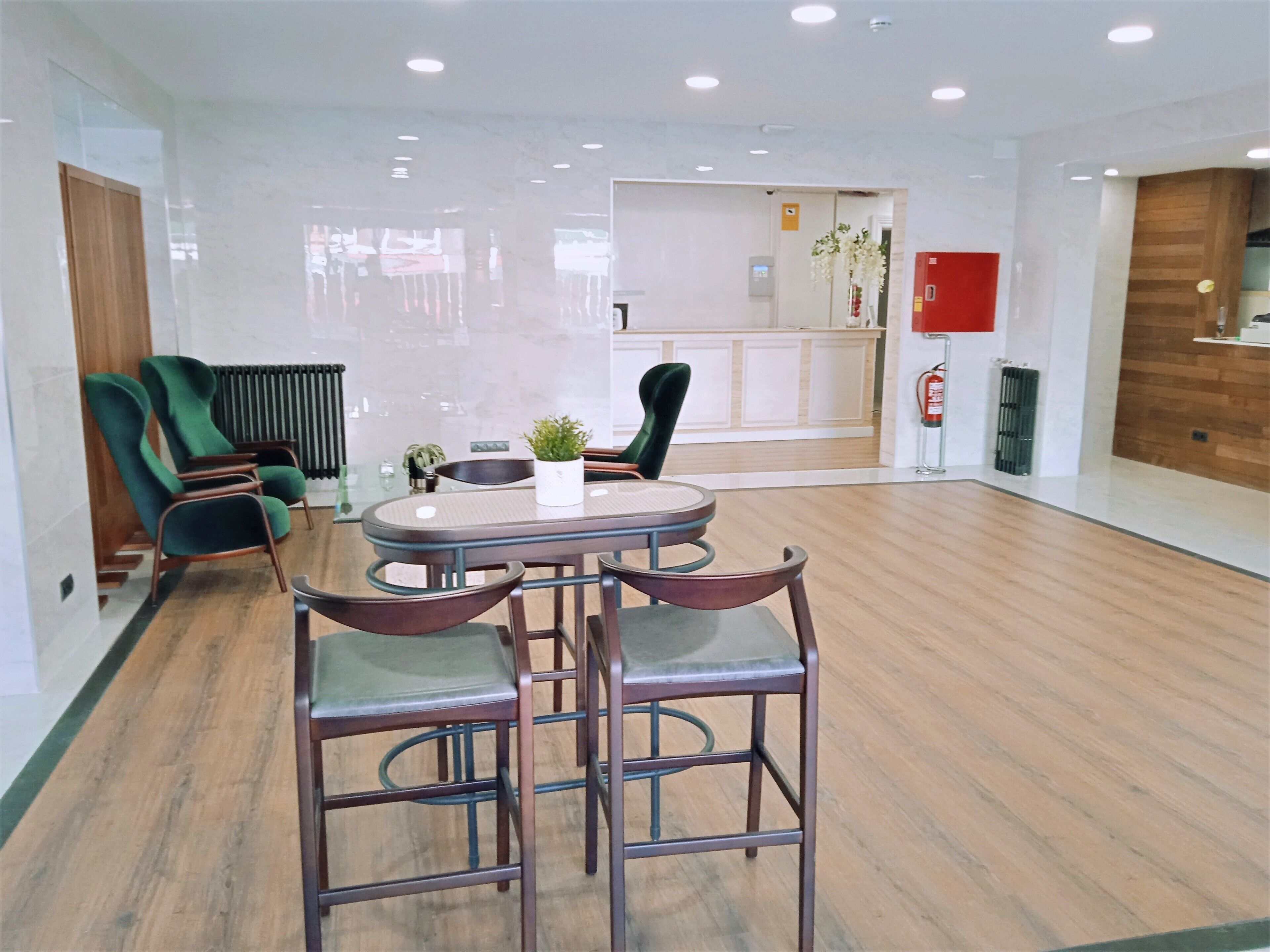 A modern dining area with a round table, two bar stools, and a potted plant.