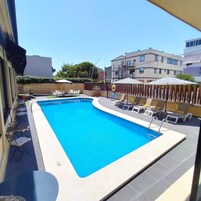 Una piscina al aire libre, sombrillas, sillones reclinables de piscina