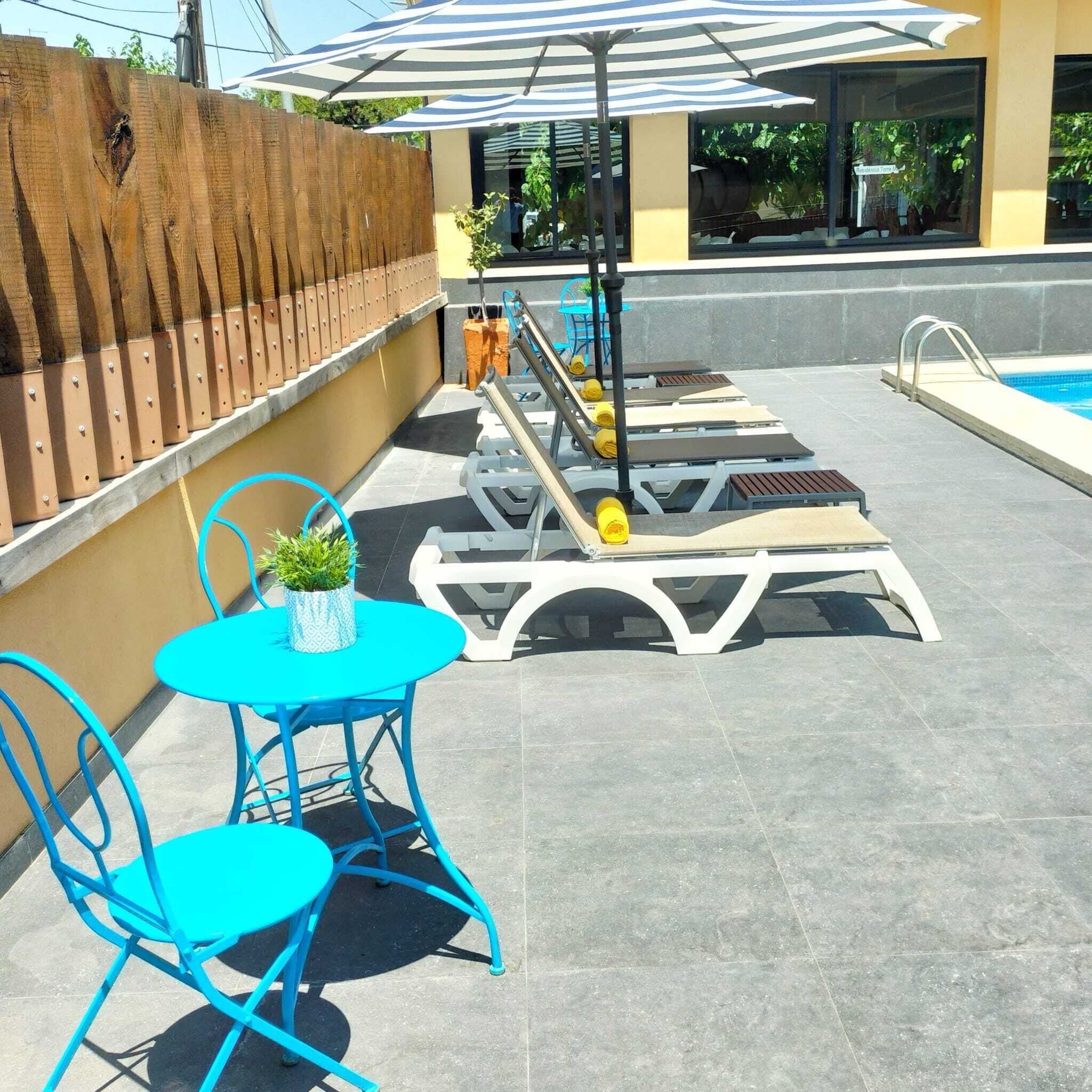 A poolside area with lounge chairs, a table, and an umbrella.