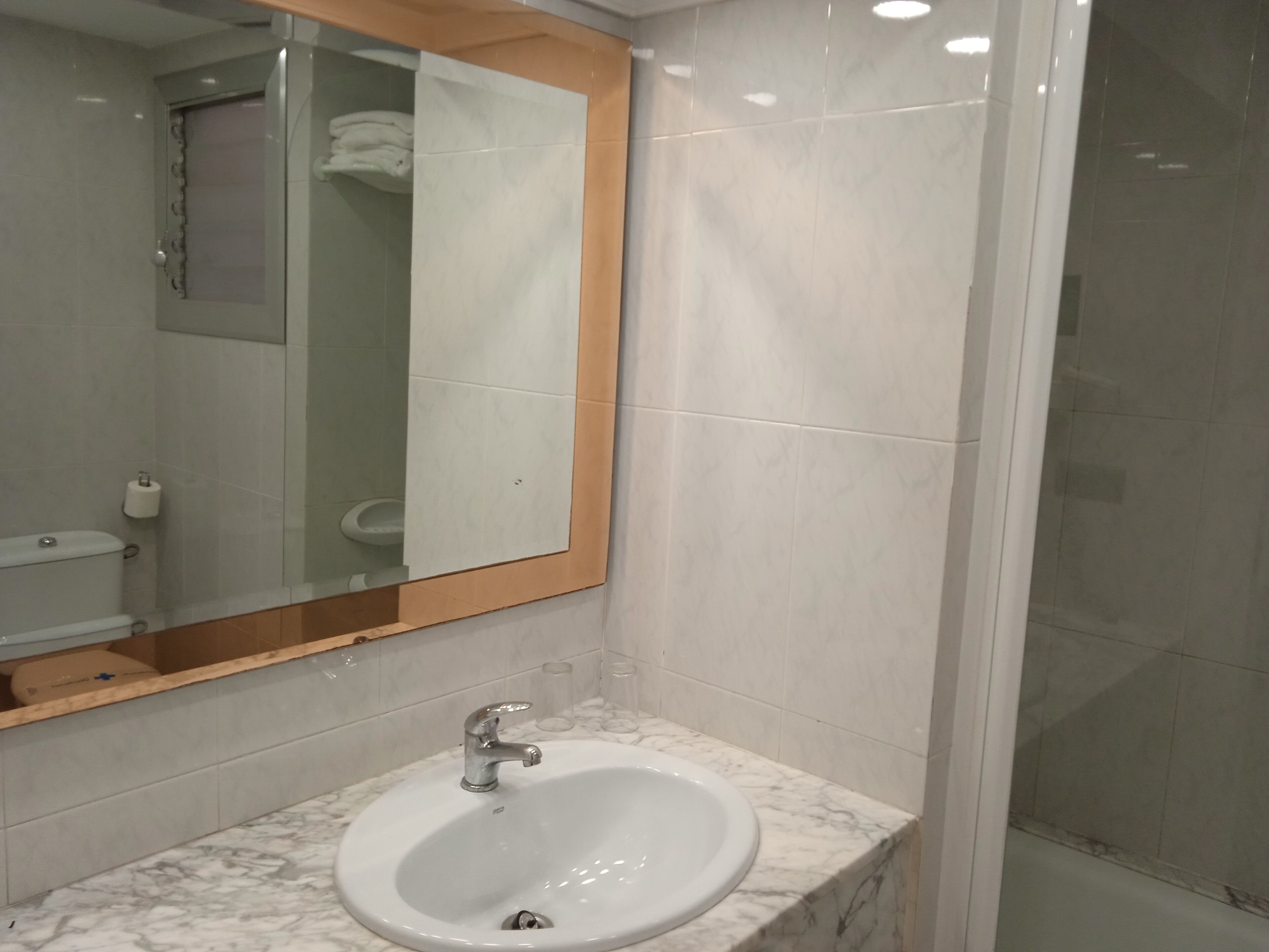 A bathroom with a white sink, a mirror, and a shower area.
