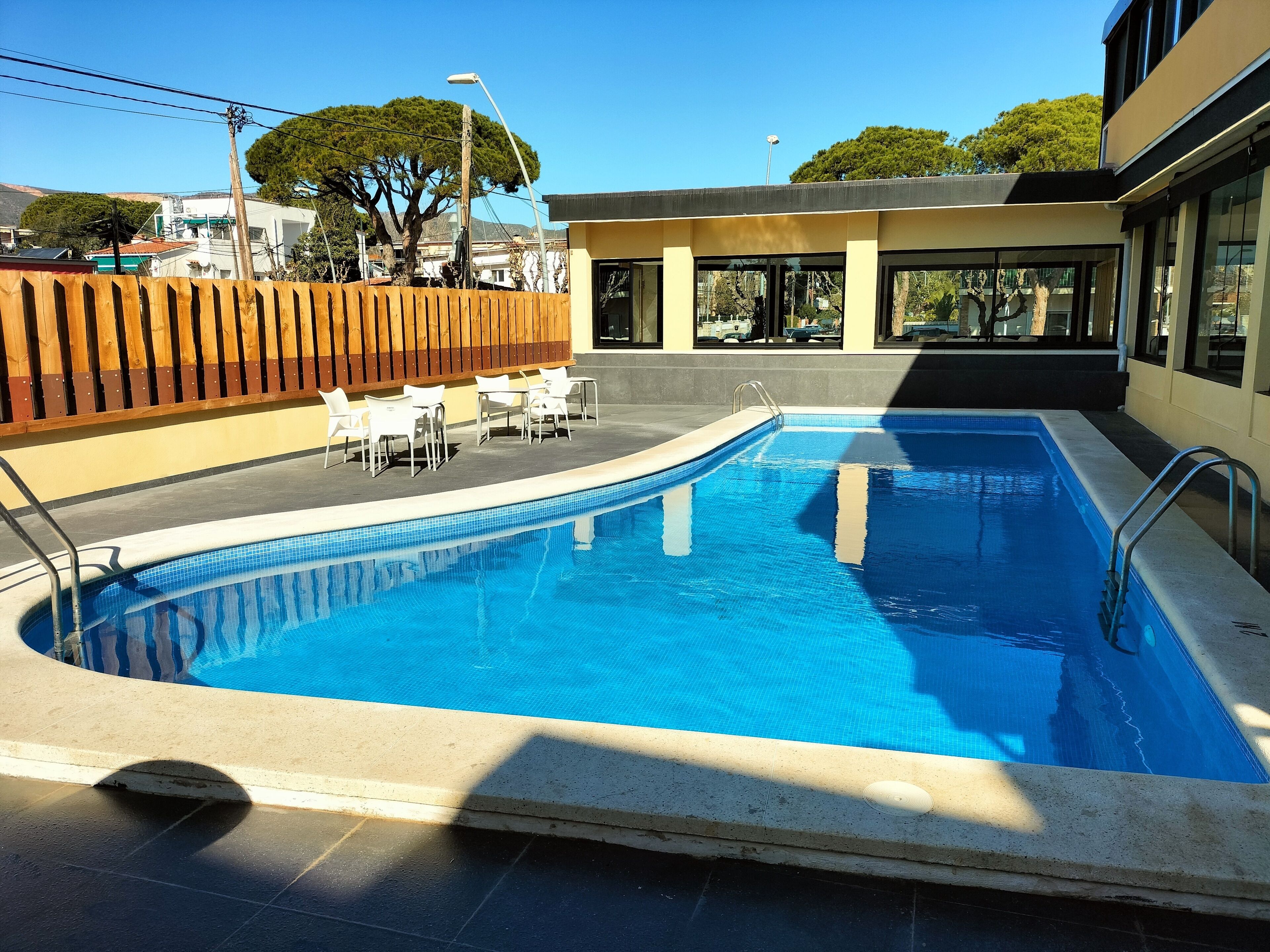 Een buitenzwembad, parasols bij het zwembad en ligstoelen