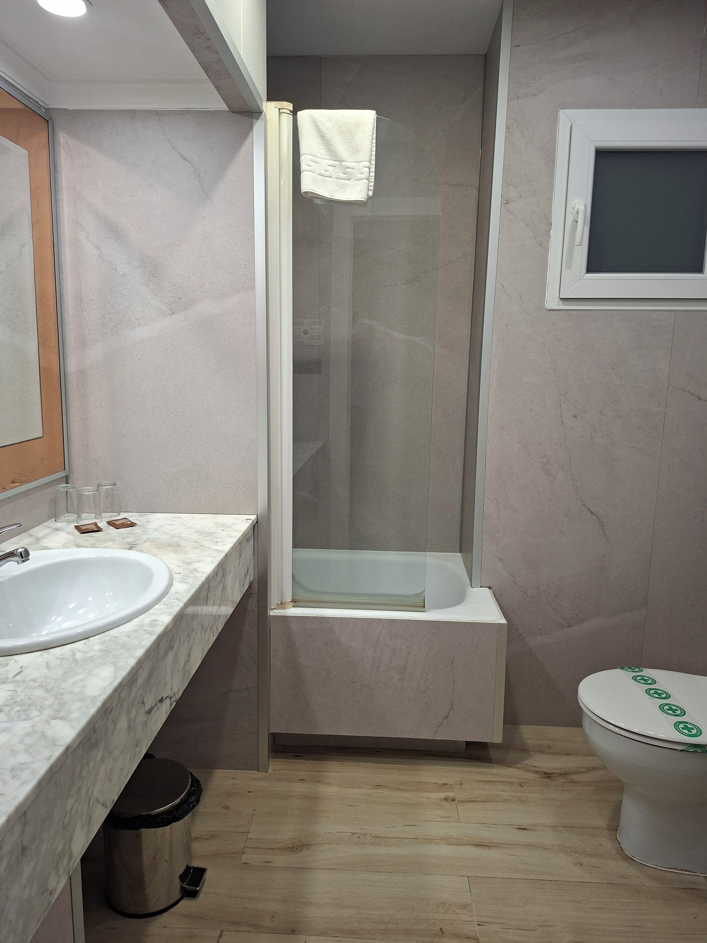 A bathroom with a marble sink, a glass-enclosed shower, a toilet, and a mirror.