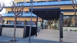 A multi-story building with a modern architectural design, featuring a covered entrance area with steps leading up to it. - Hotel 153 (Castelldefels)