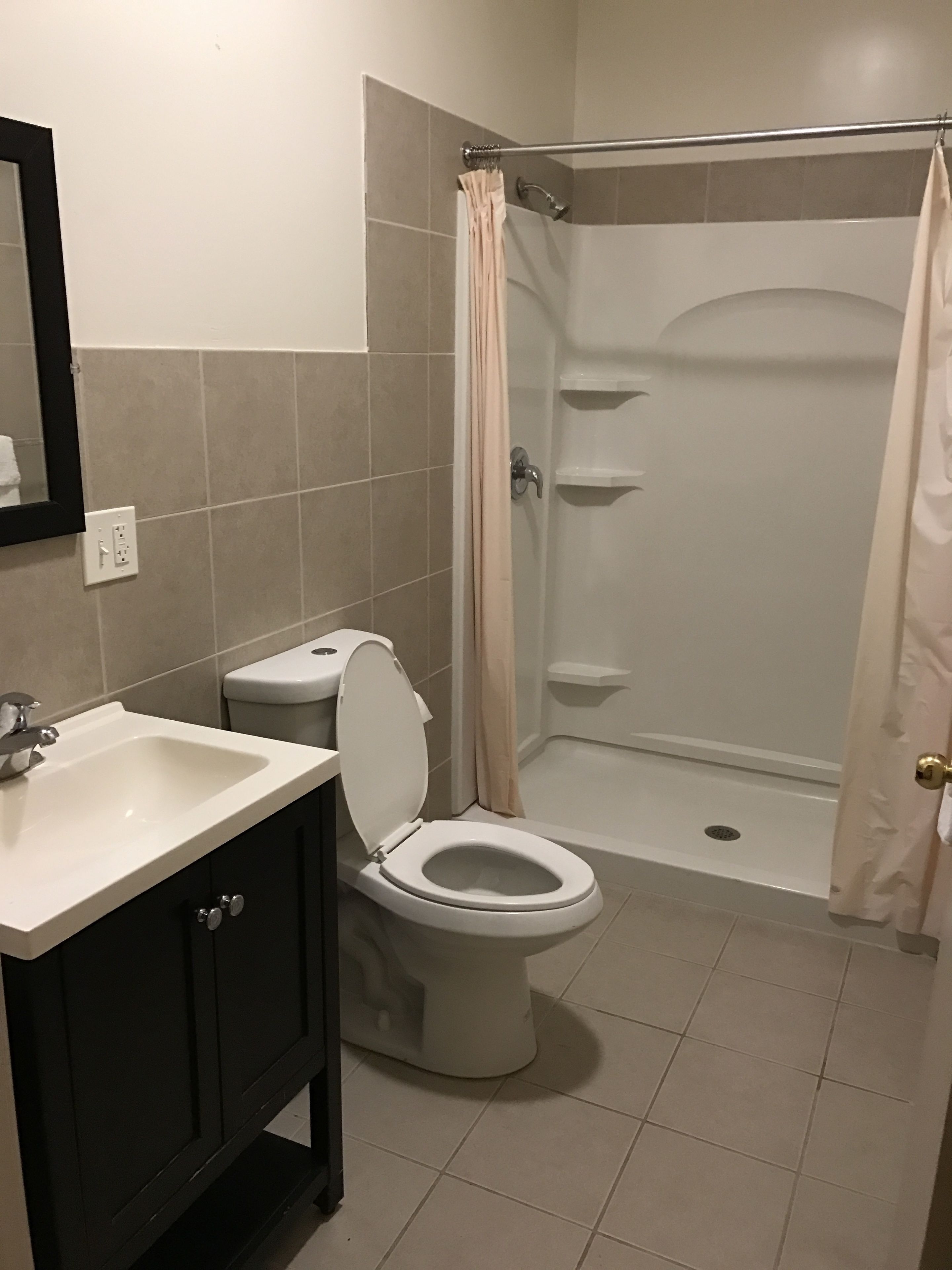 A bathroom with a toilet, sink, and shower.