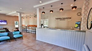 A hotel reception area with a modern design, including a reception desk, seating area, and a television screen. - Hotel Tierra Gaucha (San Carlos de Bariloche)