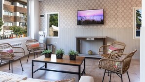 A modern living room with a sofa, wicker chairs, a coffee table, and a flat-screen TV mounted on the wall. - Hotel Tierra Gaucha (San Carlos de Bariloche)
