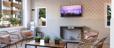 A modern living room with a sofa, wicker chairs, a coffee table, and a flat-screen TV mounted on the wall.