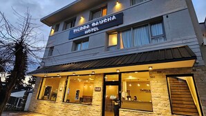 A hotel with a stone facade, multiple windows, and a sign reading "Tierra Gaugha Hotel." - Hotel Tierra Gaucha (San Carlos de Bariloche)