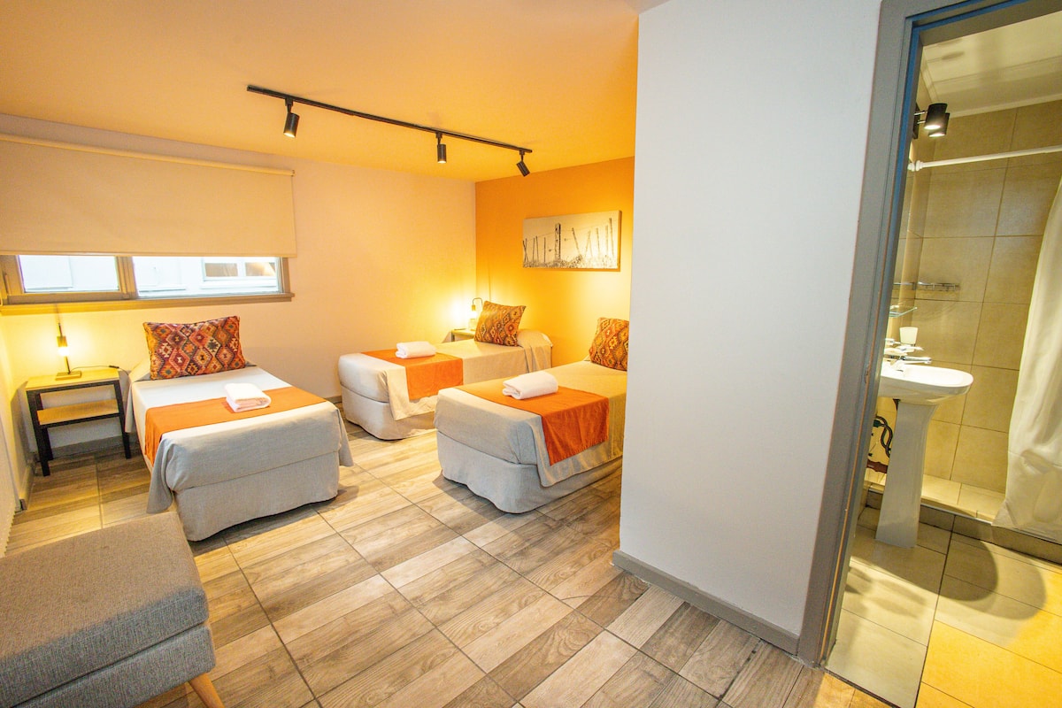 A hotel room with two beds, a sitting area, and a bathroom.