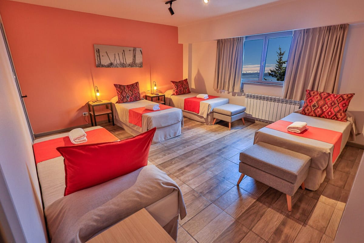A hotel room with two beds, a sofa, and a window with a view.