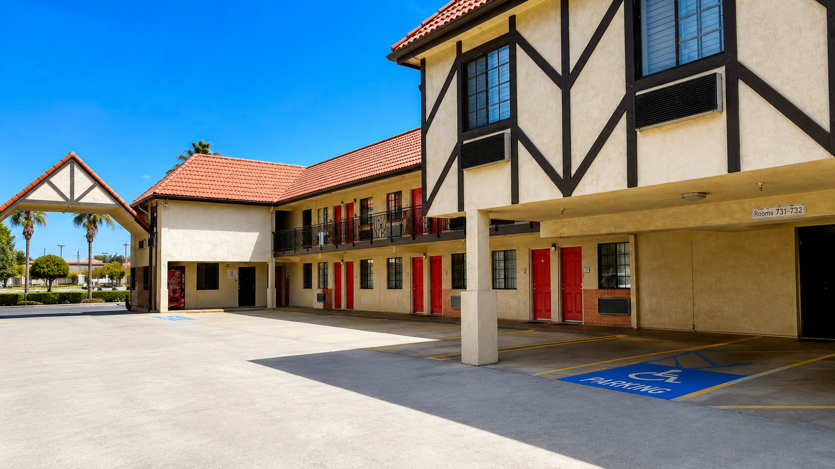 A hotel with a two-story structure, multiple rooms, and a covered parking area.