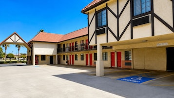 Un hotel de dos pisos, con varias habitaciones y un estacionamiento techado.