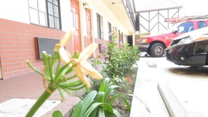 A building with a brick facade, red doors, and a red vehicle parked in front. - Executive Suites Inn (Westminster)