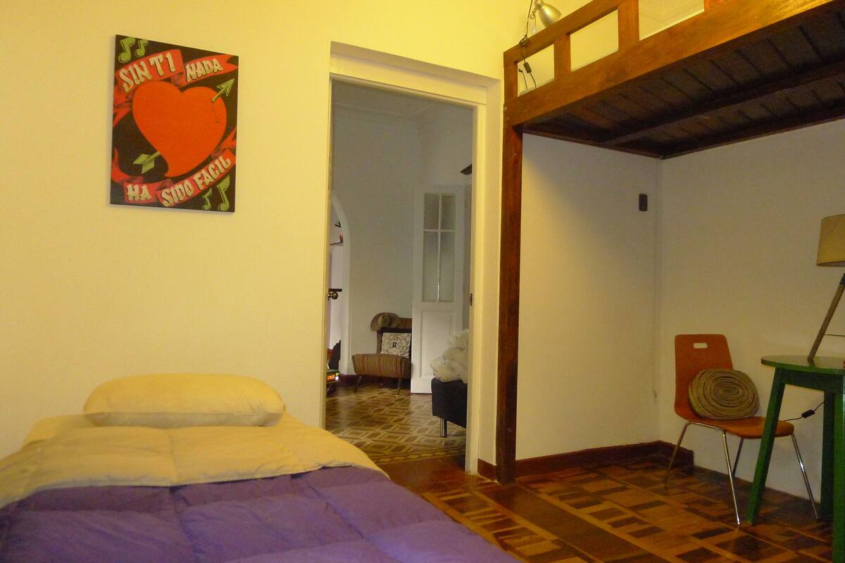 Un dormitorio con una cama, una silla y un cuadro en la pared.