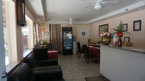 A hotel lobby with a seating area, a water dispenser, a reception desk, and a ceiling fan. - Blue Gum Motel (Willows)