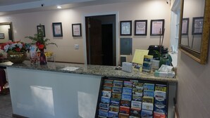 A reception desk with framed certificates on the wall, a bulletin board with travel brochures, and a plant on the counter. - Blue Gum Motel (Willows)