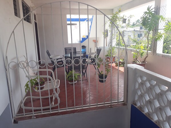 A balcony with a metal gate, a table with chairs, and potted plants. - Hotel y Bungalows Los Arcos (San Patricio Melaque)