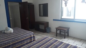 A room with two beds, a wardrobe, a small table, a mirror, and a window with curtains. - Hotel y Bungalows Los Arcos (San Patricio Melaque)