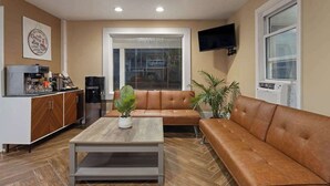 A modern living room with a sofa, coffee table, and a kitchen area with a coffee machine.