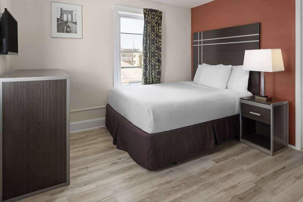 A hotel room with a bed, bedside table, and a wardrobe.