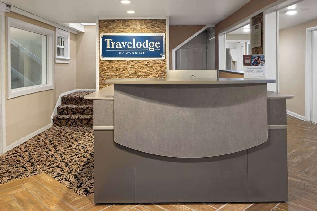 A reception desk with a sign reading 'Travelodge by Wyndham' and a patterned carpet.