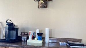 A kitchen counter with a coffee maker, a basket, and some kitchen items. - Savannah Motel (Savannah)