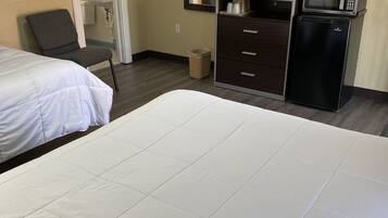 Habitación de hotel con una cama grande, una silla, un escritorio con microondas y un televisor.