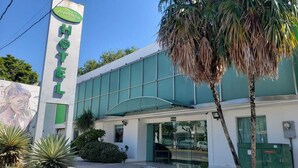 Un hotel con facciata verde, un cartello con scritto 'Aventura' e 'HOTEL' ben visibile, e un murale raffigurante una donna sulla sinistra.