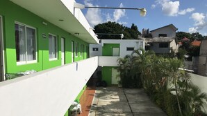 Un edificio verde e bianco con molte finestre, un vialetto lastricato e qualche area verde.