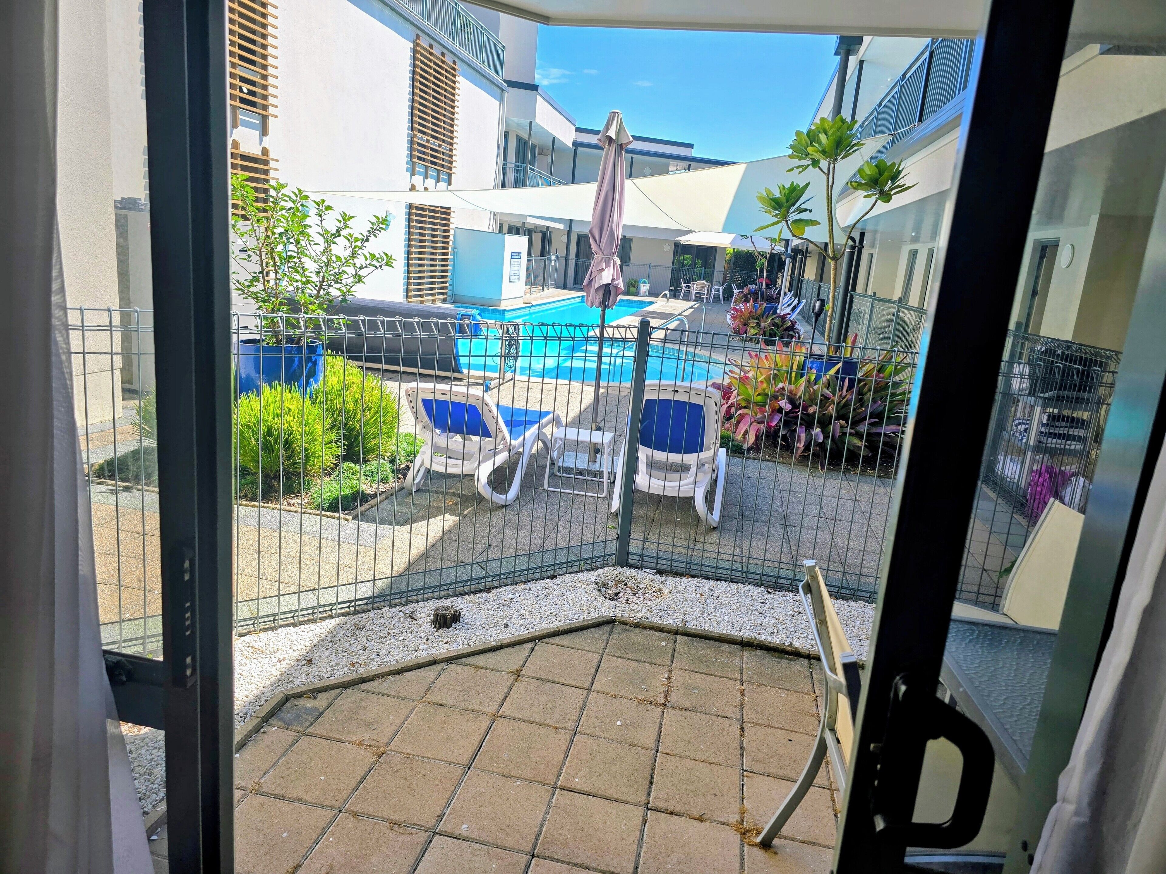 Blick auf einen Poolbereich mit Liegestühlen und einem Zaun.