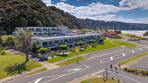 A multi-story hotel with a modern design, located near a coastal area with a view of the ocean. - Beachpoint Apartments (Ohope)