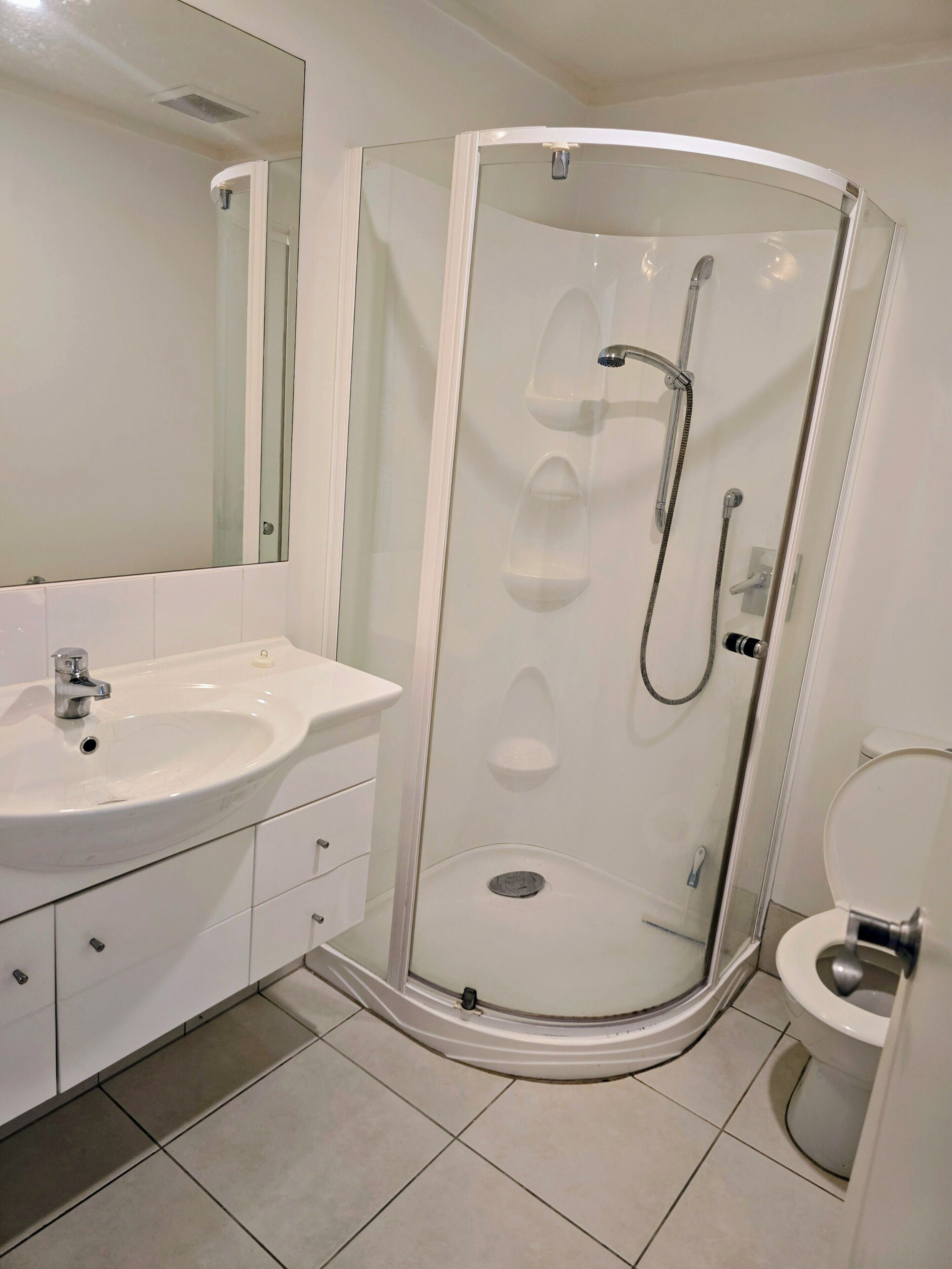 A modern bathroom with a glass-enclosed shower, a white sink, and a toilet.