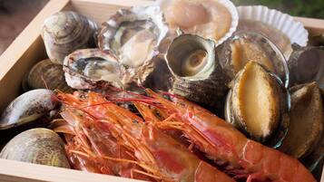 Een houten doos gevuld met diverse zeevruchten, waaronder oesters, mosselen en een grote garnaal.