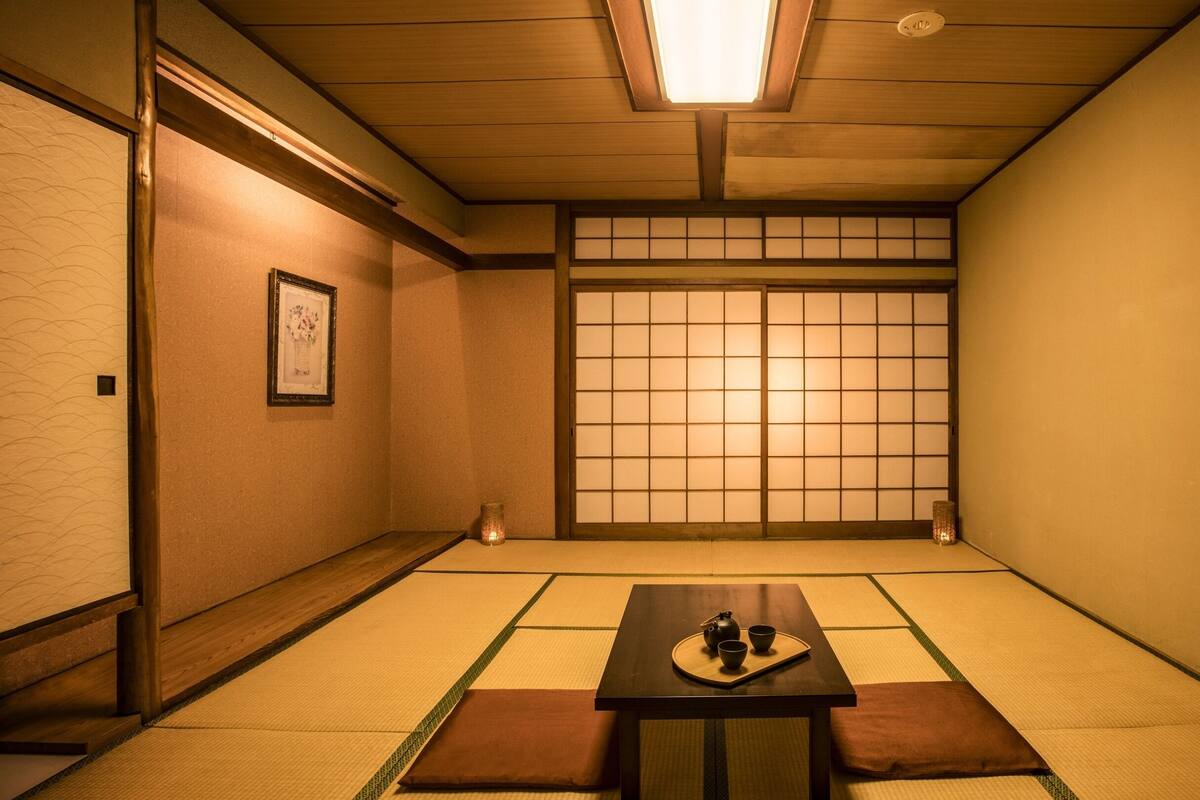 A traditional Japanese room with tatami flooring, a shoji screen, and a low table with a tea set.